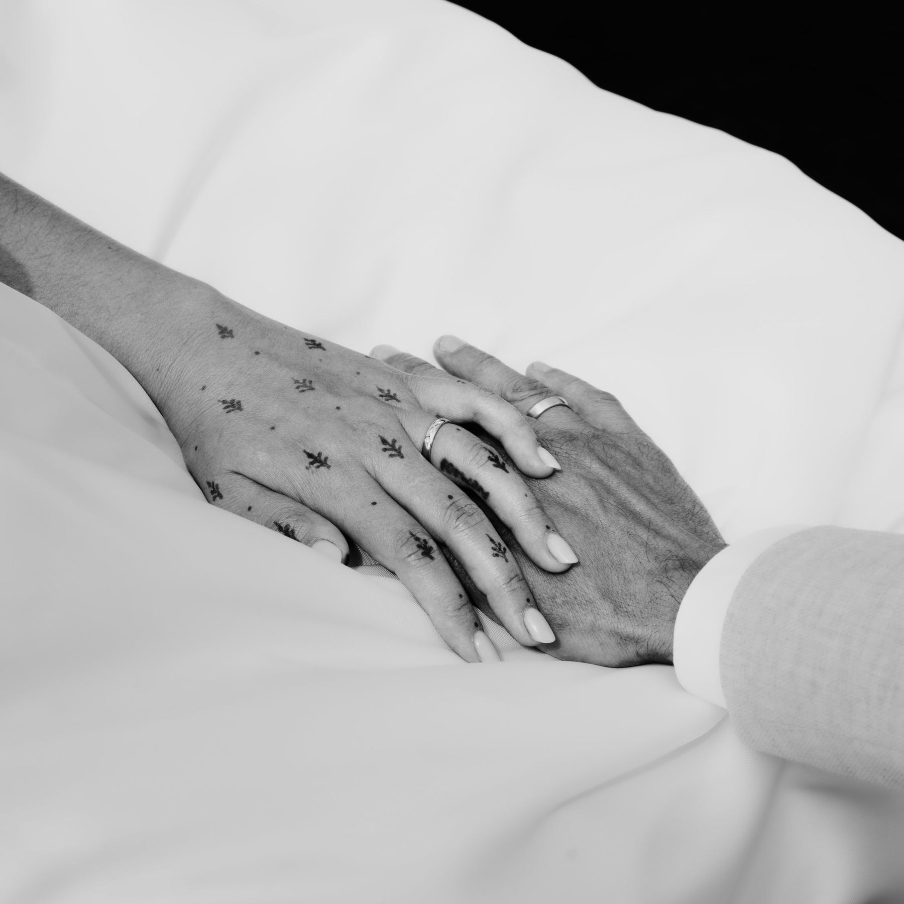 Hands with wedding rings resting on the dress, in black and white