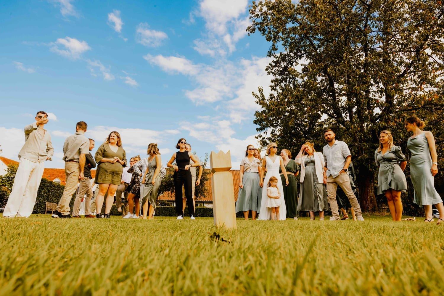 Wedding guests playing a lawn game in the garden under a blue sky